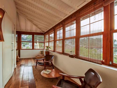 a room with chairs and a table and windows at Santa Teresa Hotel Rio de Janeiro - MGallery Collection in Rio de Janeiro