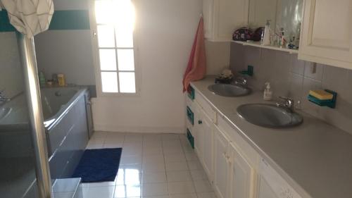 une salle de bain avec deux lavabos et une fenêtre dans l'établissement Maison vigneronne Vias centre, à Vias