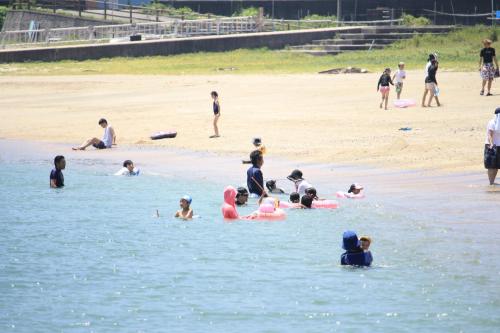 un grupo de personas en el agua en una playa en Seaside Hotel Geibousou, en Shima