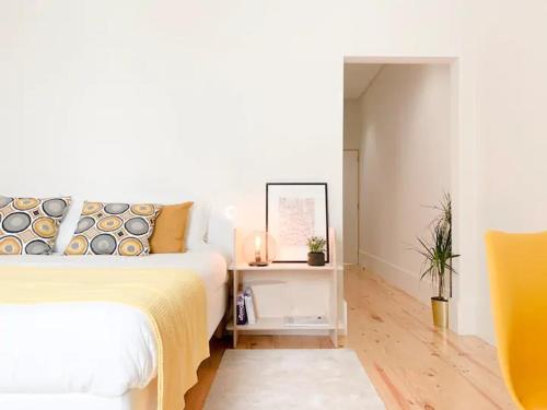 a white bedroom with a bed and a mirror at Guest House Arca de Água in Porto