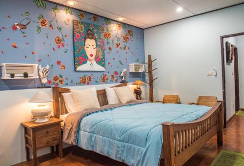 a bedroom with a blue bed with a painting on the wall at Dream Garden Villa Hotel Night Bazaar ChiangMai in Chiang Mai