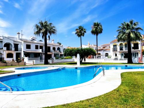 een zwembad voor een huis met palmbomen bij Bungalow de vacaciones in Torrevieja