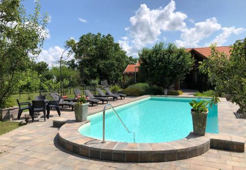 a swimming pool with chairs and a table and a house at Patrimonium Wellness Apartments in Tiszaszentimre