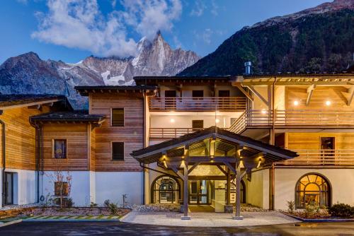 a large building with mountains in the background at Thedrus luxury apt, swimming pool, SPA & more in Chamonix-Mont-Blanc