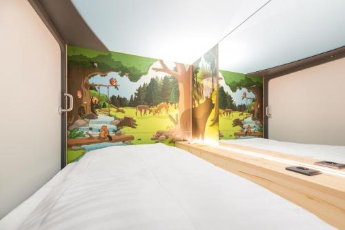 a bedroom with a wall mural of a forest at Capsule Hotel by Hyve Basel in Basel