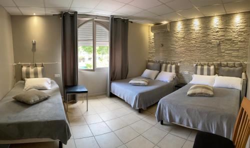 een kamer met 2 bedden en een bakstenen muur bij Hôtel Le Derby in Cagnes-sur-Mer