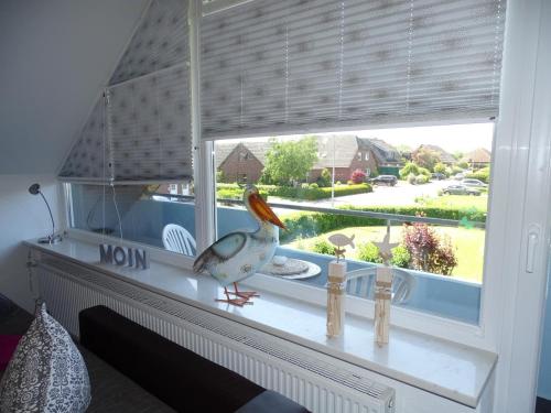 a bird sitting on a mantle in a window at 50108 Ferienhaus Cliner Sünn Whg. Baltrum in Carolinensiel