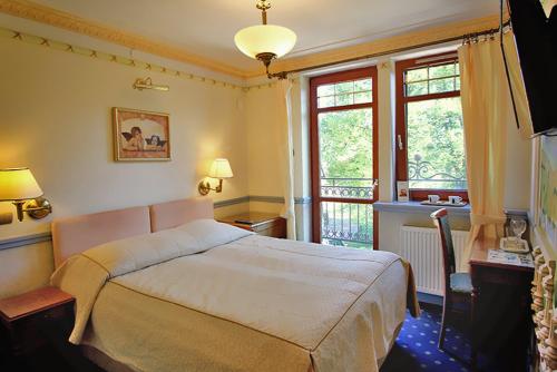 a bedroom with a large bed and a balcony at Willa Amor in Krynica Morska