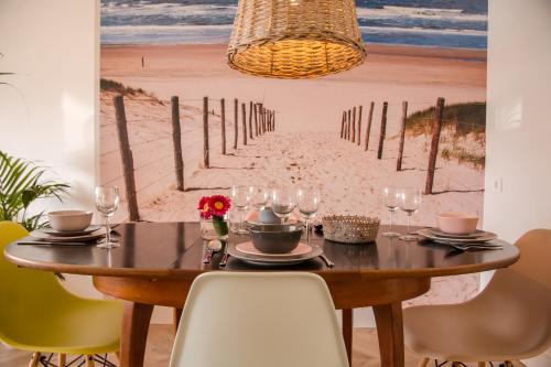 a dining room table with a painting of the beach at Beachhouse Anna, 1 minute walk to the beach and centre of Katwijk, Free private parking next to the house ! in Katwijk aan Zee
