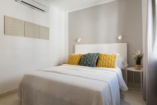 a white bedroom with a white bed with yellow pillows at Villa Abeto in Yaiza