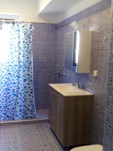a bathroom with a sink and a shower curtain at Ithaca's Poem Apartments in Vathi, Ithaka