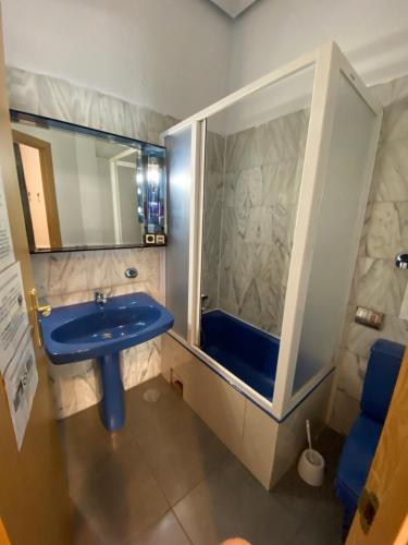 y baño con lavabo azul y espejo. en Barbieri Sol Hostel, en Madrid