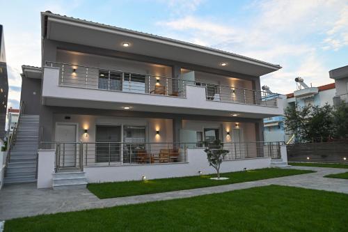 a large house with a balcony and a yard at Faidra Apartments in Néa Péramos