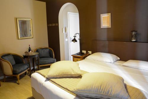 a hotel room with two beds and two chairs at Washington Apartments al Vittoriale in Gardone Riviera