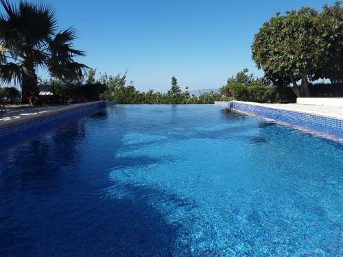 una gran piscina de agua azul con árboles en el fondo en Villa Bella Vista, en Droushia