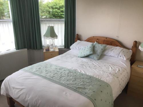 a bedroom with a white bed with green curtains and windows at Drakewalls Bed And Breakfast in Gunnislake