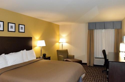 um quarto de hotel com uma cama e uma cadeira em Sierra Inn Minot em Minot