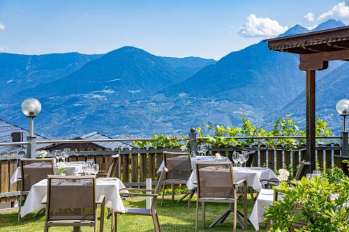 a restaurant with tables and chairs with mountains in the background at Hotel Stefanie in Tirolo