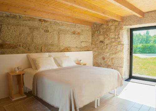 una camera da letto con un letto in un muro di pietra di Casas d'Oliva a Caramulo