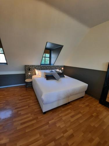 a bedroom with a white bed and a wooden floor at La Bergerie de Lives in Namur