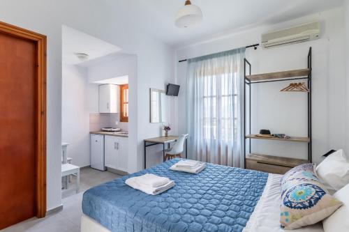 a bedroom with a blue bed and a kitchen at Nepheles in Skopelos Town