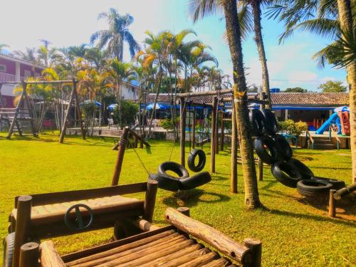um parque com baloiços e um banco e palmeiras em Hotel Pousada Vivendas do Sol e Mar em Caraguatatuba