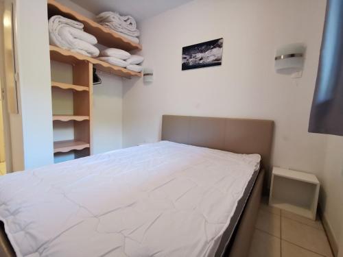 une petite chambre avec un lit et des étagères avec des serviettes dans l'établissement Appartement 4 personnes Les Orres 1800 au pied des pistes, aux Orres