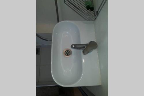 a white sink in the corner of a bathroom at Air conditioned STUDIO in quite garden with barbecue Athens in Athens