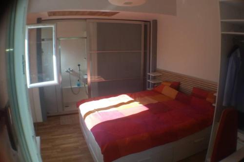 um quarto com uma cama com um edredão vermelho e uma janela em Entire Studio in quite garden with barbecue Athens em Atenas
