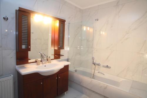 a bathroom with a sink and a shower and a tub at Pirofani Villa Apartments in Apolpaina