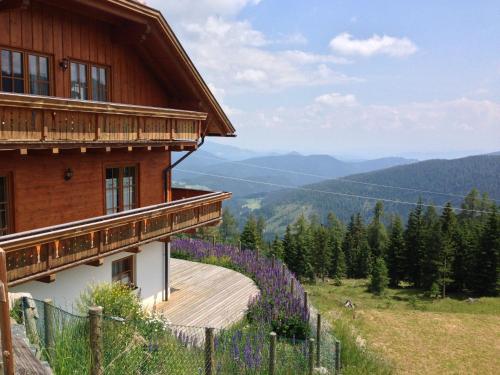 a house on a hill with a fence and purple flowers at Almhaus Karantanien in Hochrindl