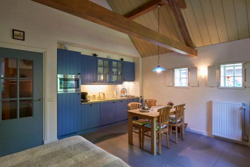 a kitchen with blue cabinets and a table and chairs at Huys en Hoff Aen Den Haspel in Oirschot