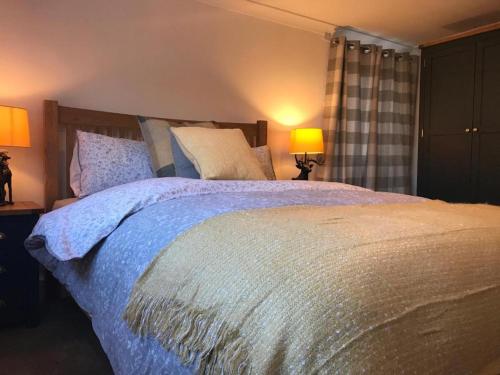 a bedroom with a large bed with blue sheets and pillows at Ye Olde Saddlery B&B in Neatishead