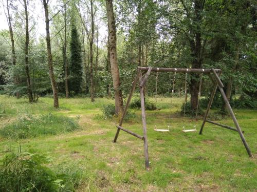 an old swing set in a field with trees at Les Gîtes du Château de Passillé in Parigné