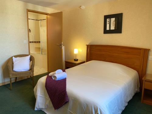 ein Hotelzimmer mit einem Bett und einem Stuhl in der Unterkunft Hôtel SPA Le Tosny in Épaignes
