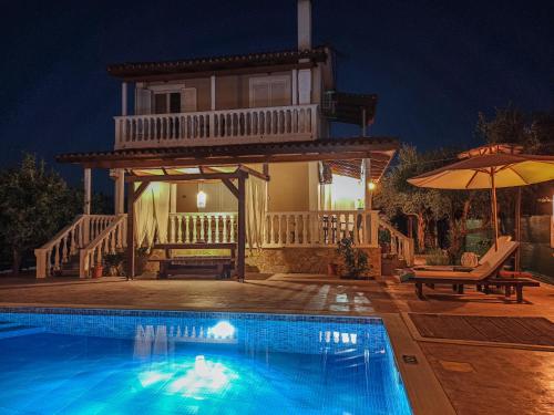 a villa with a swimming pool at night at Villa Lina in Pandokrátor