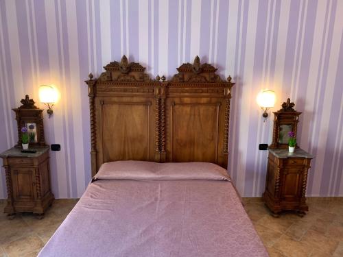 um quarto com uma grande cama de madeira e 2 mesas de cabeceira em Palazzo Gentilizio de Maffutiis em Auletta