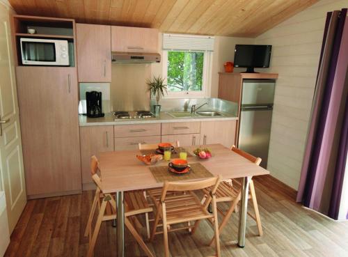 a kitchen with a table and chairs in a kitchen at Camping La Loire Fleurie in Le Perrier