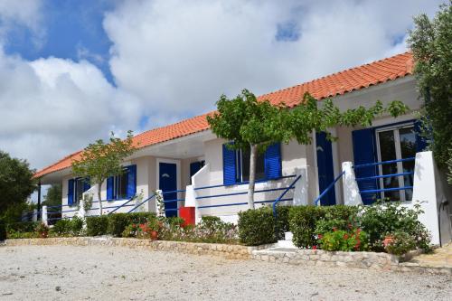 a house with blue shutters and a yard at Panorama Apartments in Methoni