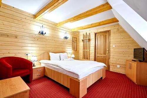 a bedroom with a bed and a red chair at Casa Chira in Vişeu de Sus