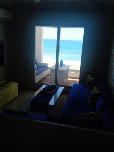 a living room with a blue couch and a view of the ocean at Appartement résidence Atlantic 1 in Kenitra