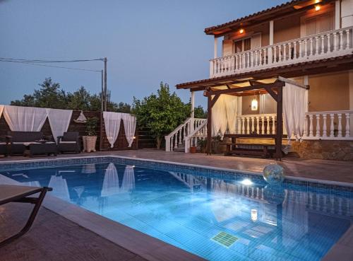 a swimming pool in front of a house at Villa Lina in Pandokrátor