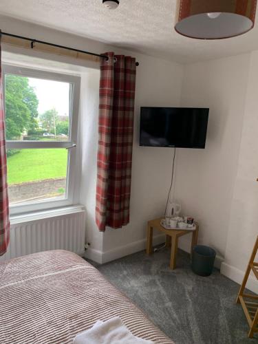 a bedroom with a bed and a tv and a window at DOVENBY SHIP in Tallentire