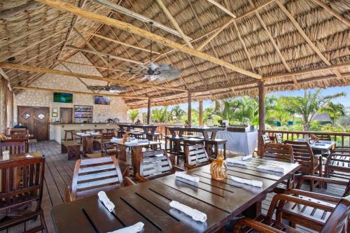 um restaurante com mesas e cadeiras de madeira e um tecto em Sirenian Bay Resort -Villas & All Inclusive Bungalows em Aldeia de Placencia