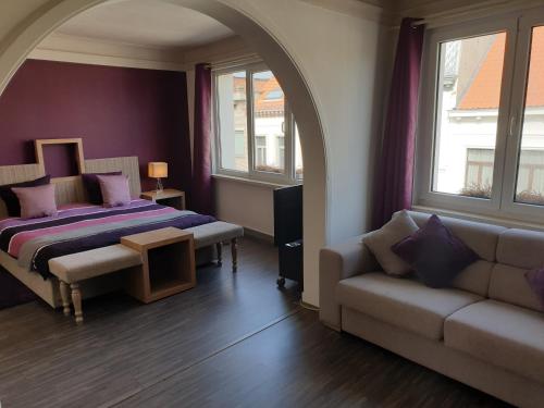 a bedroom with a bed and a couch and windows at B&B Luxe Suites 1-2-3 in Antwerp