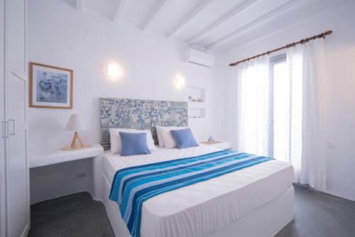 a white bedroom with a large bed and a window at Myconian Relax House with swimming pool in Ano Mera
