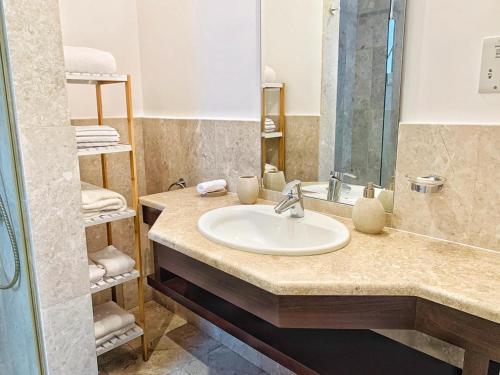 een badkamer met een wastafel, een spiegel en handdoeken bij Sifa Getaway in Muscat
