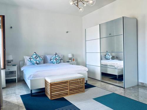 een witte slaapkamer met een groot bed en een spiegel bij Sifa Getaway in Muscat