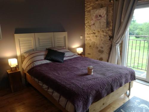 a bedroom with a bed with a purple comforter and a window at La Chabottine Vercors in Saint-Just-de-Claix