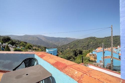 a chair sitting on the edge of a roof with a view at Hotel Restaurante Bandolero in Júzcar